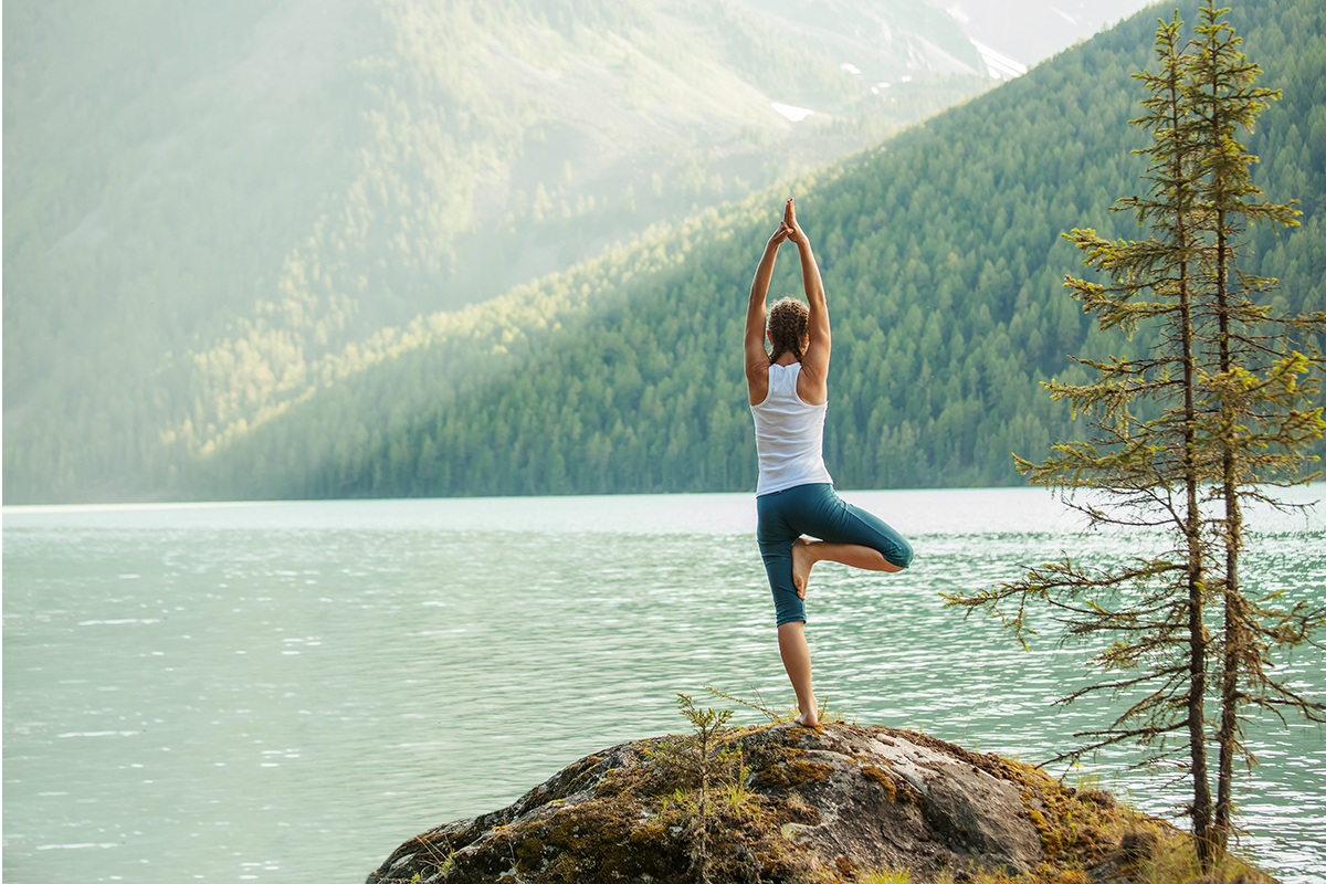 yoga instructor posing in front of a peaceful lake setting